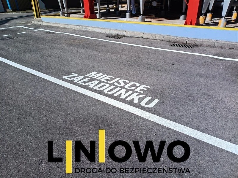 Napis MIEJSCE ZAŁADUNKU namalowany na asfalcie przy hali