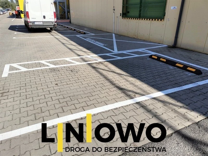 Białe linie miejsc postojowych na kostce brukowej przy budynku