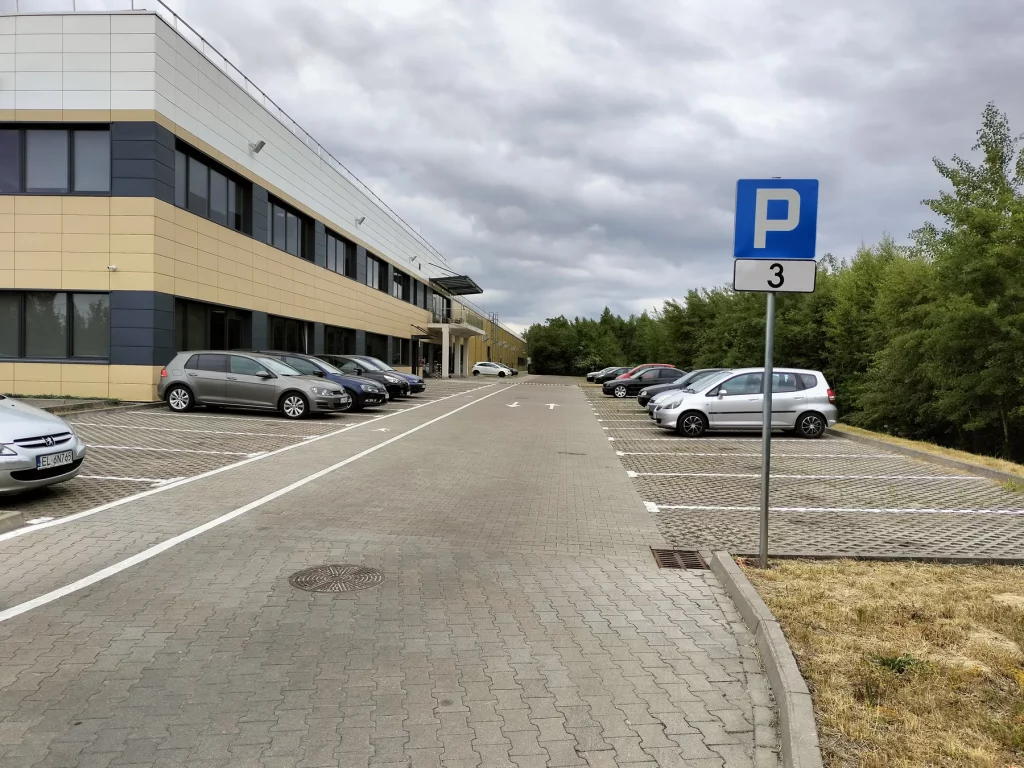 Parking przy budynku zakładu z oznakowaniem poziomym i znakiem P