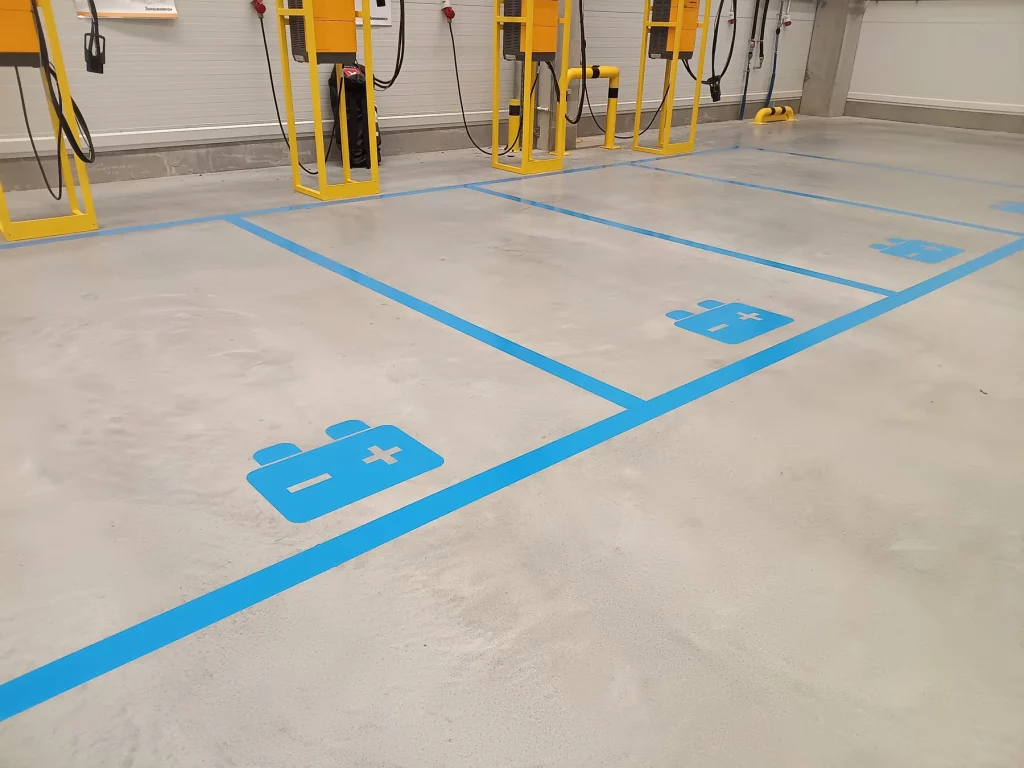 Stanowiska ładowania wózków elektrycznych oznaczone niebieskimi liniami i piktogramami